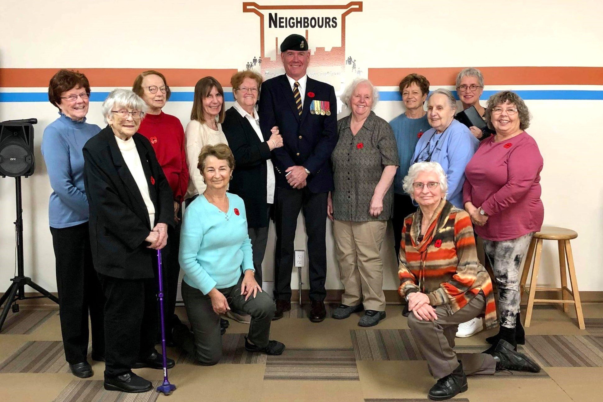 Older adults with man in military uniform at Neighbours